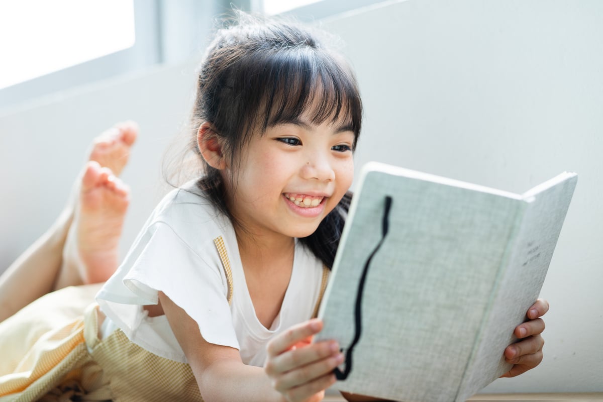 Asian Child Reading Book at Home